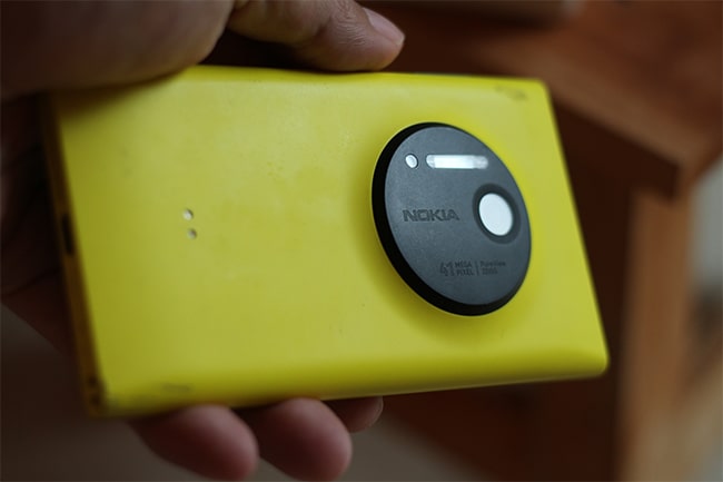 Hand håller gul mobil med svart kameraö med texten nokia.